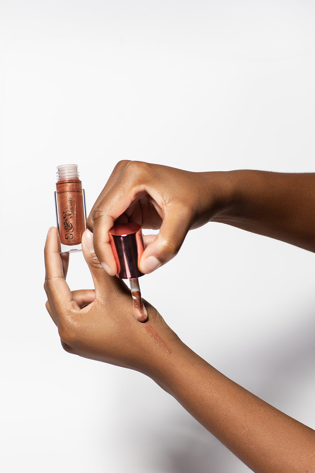 Person applying a metallic lip gloss to their lips with a white background