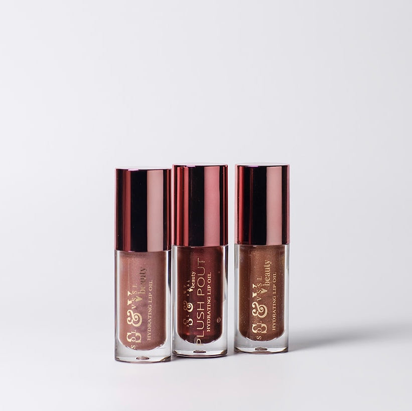 Three lip oil bottles with bronze caps and labels on a light gray background
