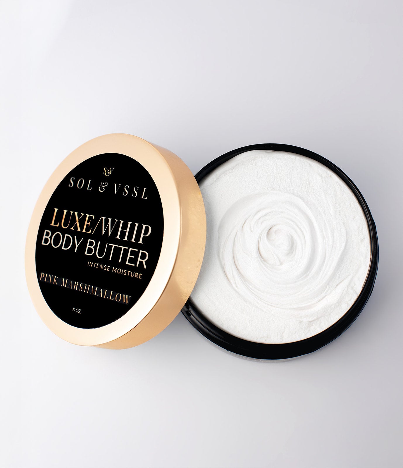 Open container of Luxe Whip Body Butter with visible cream inside on a light gray background